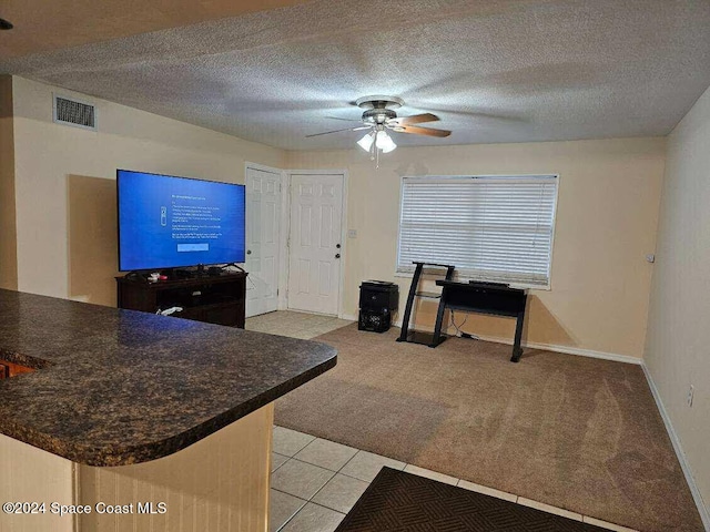 interior space with light carpet, a textured ceiling, and ceiling fan