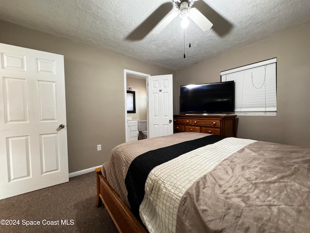 bedroom with a textured ceiling, ensuite bathroom, dark carpet, and ceiling fan