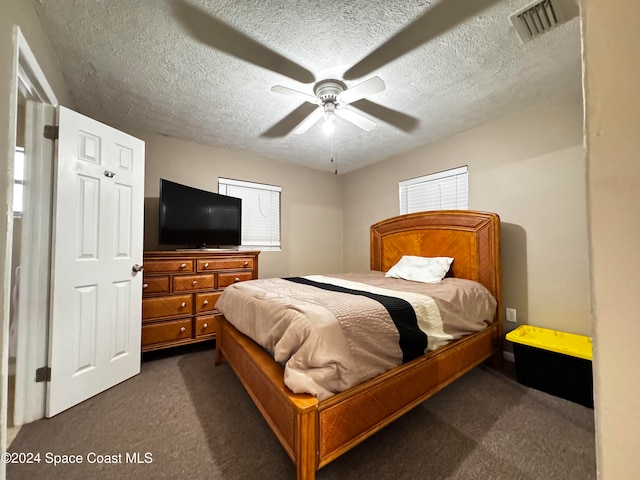 carpeted bedroom featuring ceiling fan and a textured ceiling