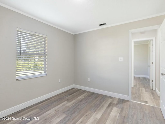 empty room with ornamental molding and light hardwood / wood-style flooring