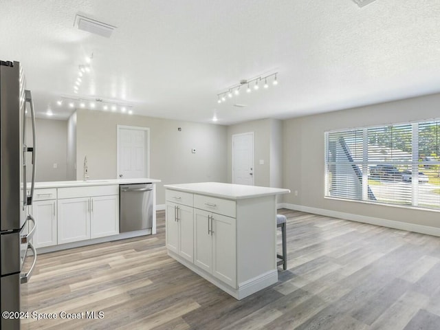 kitchen featuring a center island, white cabinets, light wood-type flooring, and appliances with stainless steel finishes