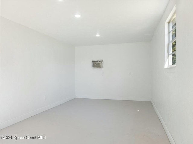 spare room featuring concrete flooring and an AC wall unit