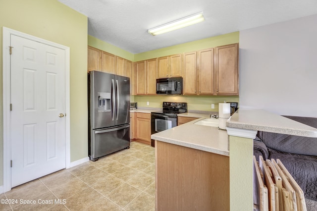 kitchen featuring a peninsula, black appliances, light brown cabinets, and light countertops