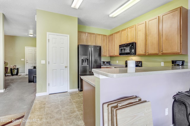 kitchen featuring light brown cabinets, black appliances, a textured ceiling, light colored carpet, and kitchen peninsula