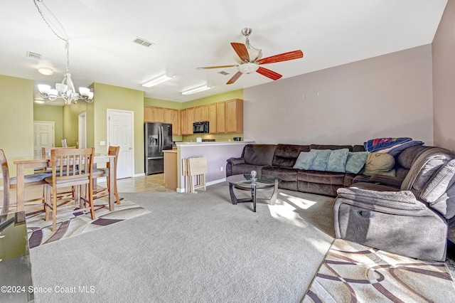 living room featuring light carpet, ceiling fan with notable chandelier, visible vents, and baseboards