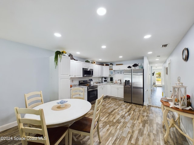 kitchen with sink, white cabinets, stainless steel appliances, and light hardwood / wood-style floors