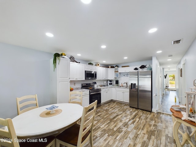 kitchen featuring white cabinets, stainless steel appliances, light hardwood / wood-style floors, and sink