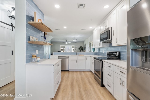 kitchen featuring a barn door, white cabinetry, sink, and stainless steel appliances