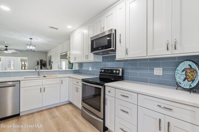 kitchen with appliances with stainless steel finishes, tasteful backsplash, ceiling fan, light hardwood / wood-style floors, and white cabinetry