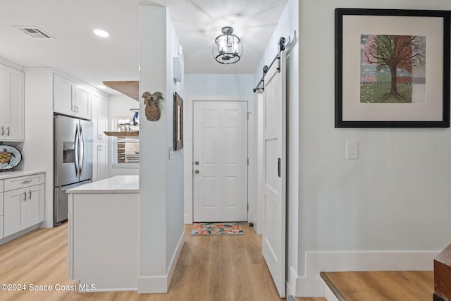 corridor featuring a barn door and light hardwood / wood-style flooring