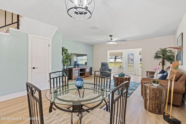 living room featuring light hardwood / wood-style floors and ceiling fan with notable chandelier