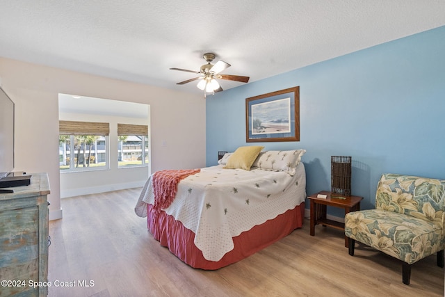 bedroom featuring ceiling fan, a textured ceiling, and light wood-type flooring