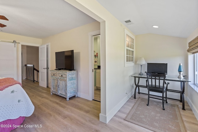 bedroom featuring a barn door and light hardwood / wood-style flooring