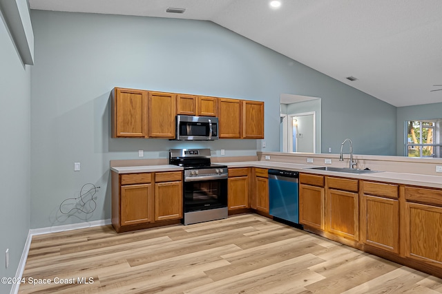 kitchen with appliances with stainless steel finishes, light wood-type flooring, high vaulted ceiling, and sink