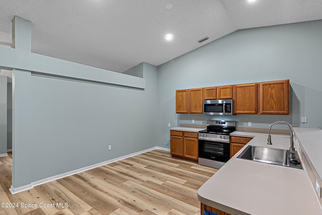 kitchen with sink, light hardwood / wood-style flooring, high vaulted ceiling, a textured ceiling, and appliances with stainless steel finishes