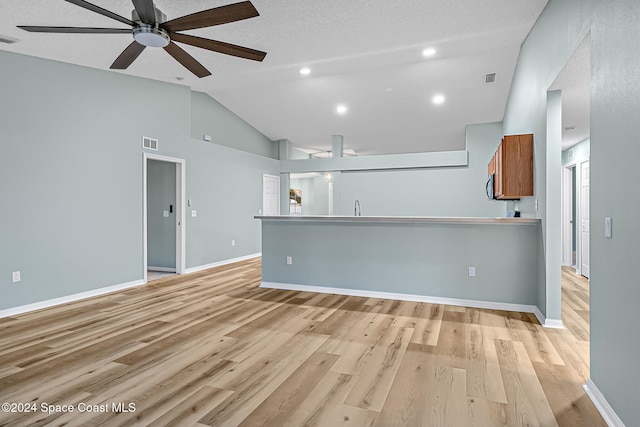 unfurnished living room featuring a textured ceiling, light wood-type flooring, high vaulted ceiling, and ceiling fan