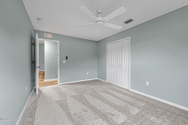 unfurnished bedroom featuring carpet flooring, ceiling fan, a closet, and a textured ceiling