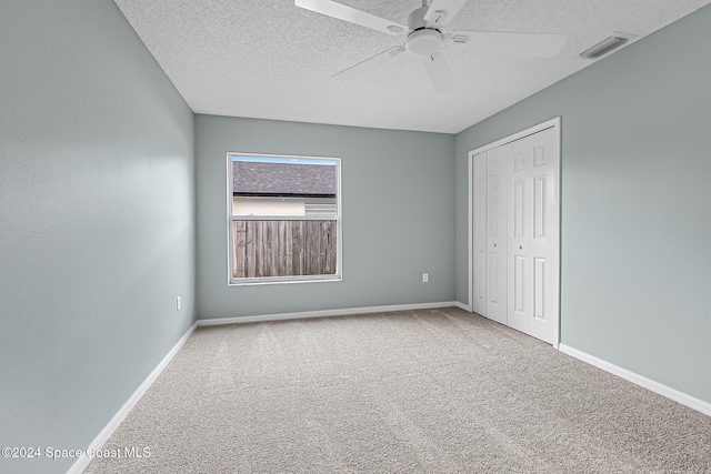 unfurnished bedroom with carpet flooring, ceiling fan, a closet, and a textured ceiling