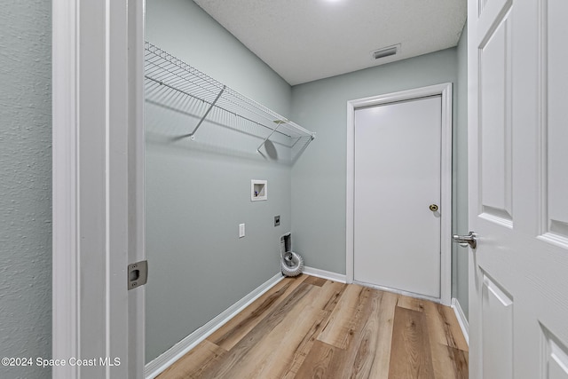 laundry area featuring electric dryer hookup, washer hookup, a textured ceiling, and light wood-type flooring