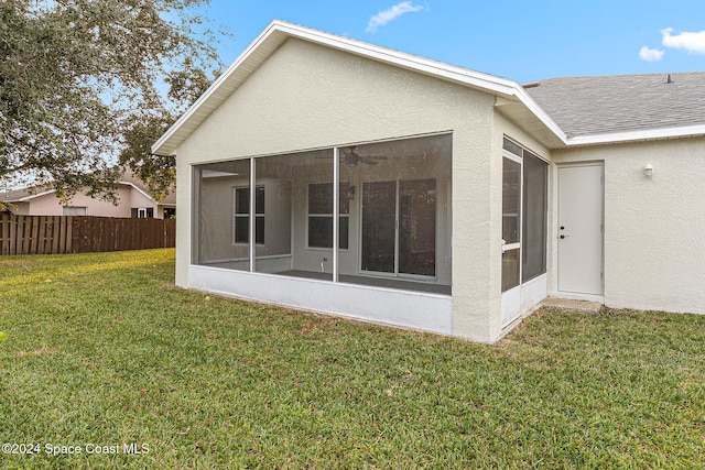 rear view of property with a lawn and a sunroom