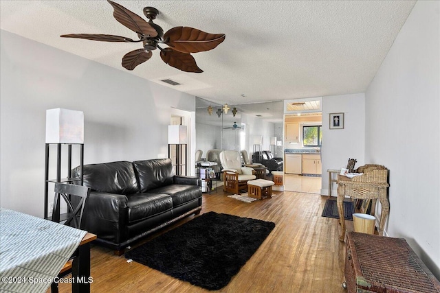 living room with hardwood / wood-style flooring, ceiling fan, and a textured ceiling