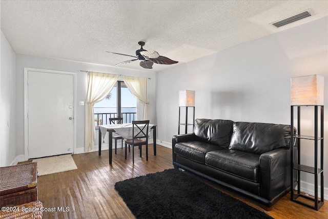 living room featuring hardwood / wood-style flooring, ceiling fan, and a textured ceiling