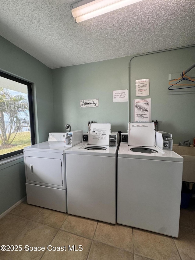 laundry room with light tile patterned floors, washing machine and dryer, and a textured ceiling