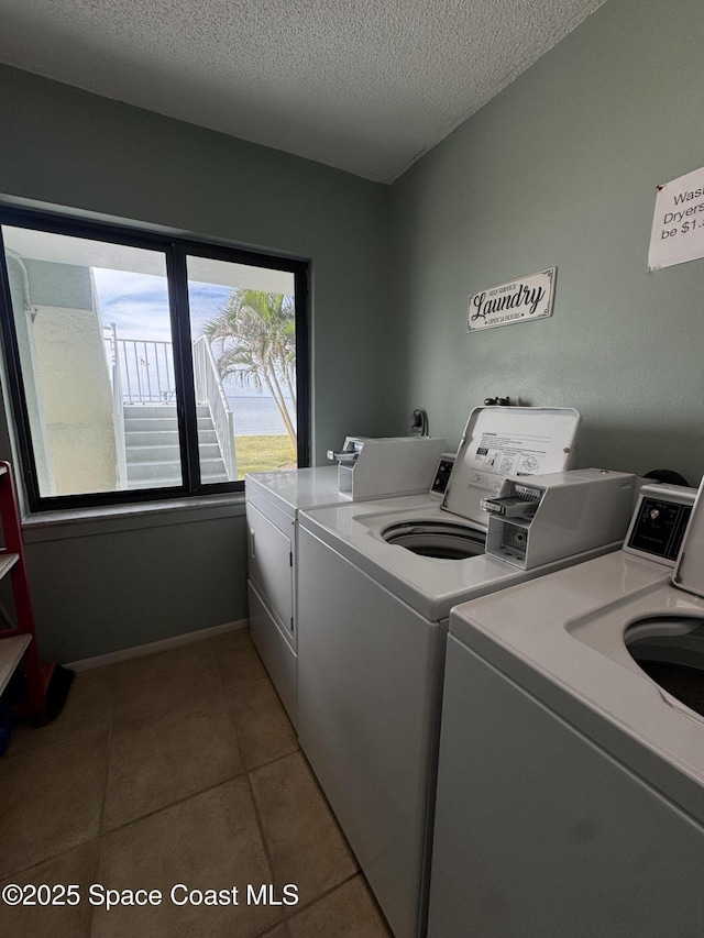 laundry room with washer and clothes dryer, a textured ceiling, and light tile patterned floors