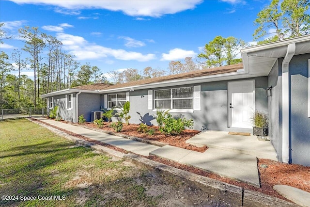 view of front of property with central AC unit and a front lawn