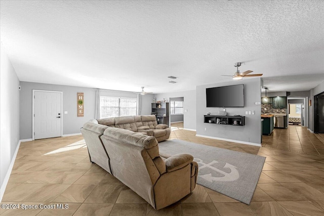 living room with ceiling fan, light tile patterned floors, and a textured ceiling