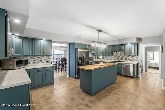 kitchen with wood counters, tasteful backsplash, pendant lighting, a kitchen island, and appliances with stainless steel finishes