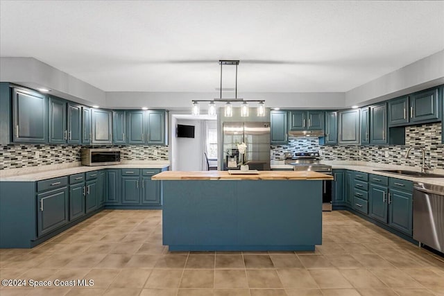 kitchen featuring appliances with stainless steel finishes, backsplash, blue cabinets, sink, and pendant lighting