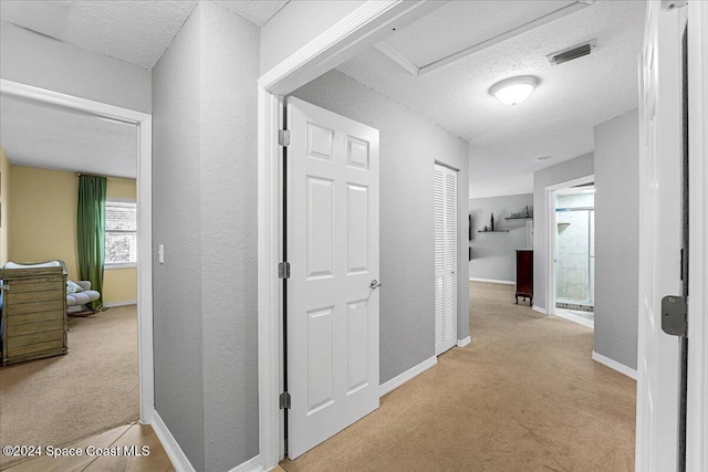 hall with a textured ceiling and light carpet