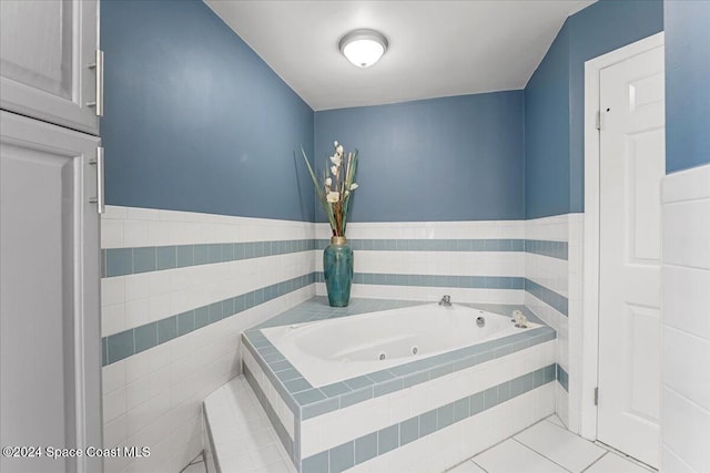 bathroom with tiled tub, tile patterned flooring, and tile walls