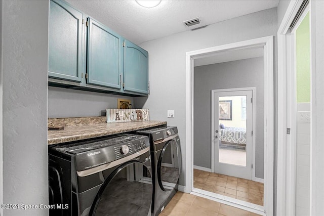 laundry area featuring light tile patterned flooring, cabinets, independent washer and dryer, and a textured ceiling