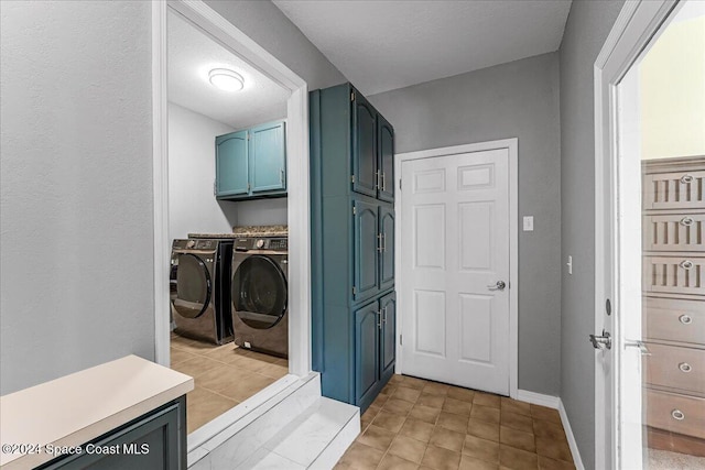 clothes washing area with separate washer and dryer and cabinets