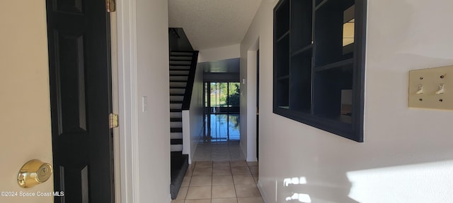 corridor with light tile patterned flooring and a textured ceiling