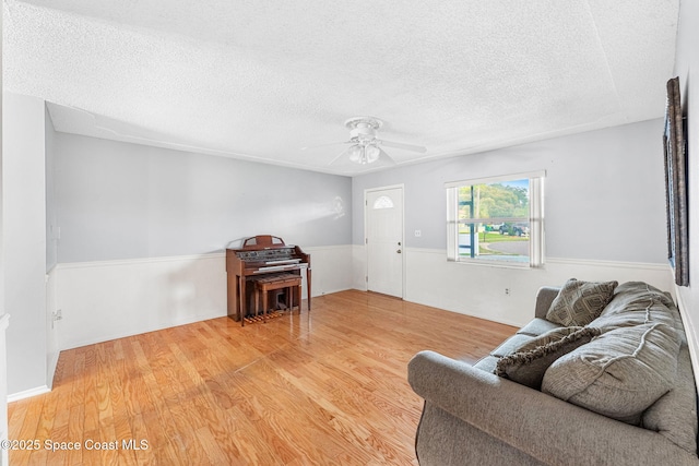 living room with ceiling fan, hardwood / wood-style floors, and a textured ceiling