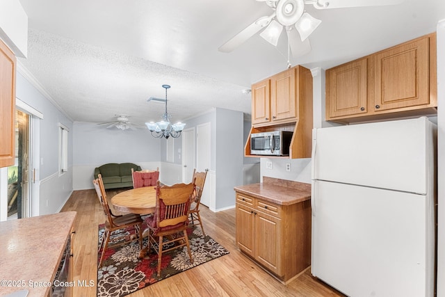 dining area with ceiling fan with notable chandelier, light hardwood / wood-style floors, a textured ceiling, and ornamental molding