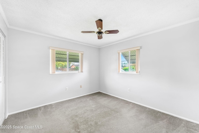 carpeted empty room featuring a textured ceiling, ceiling fan, and crown molding