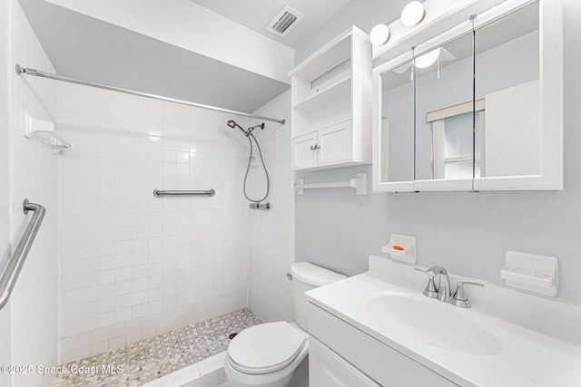 bathroom featuring vanity, toilet, and tiled shower