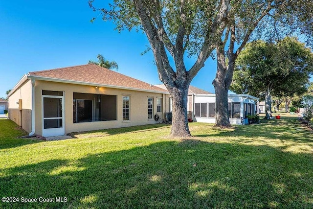 rear view of property featuring a lawn and central air condition unit