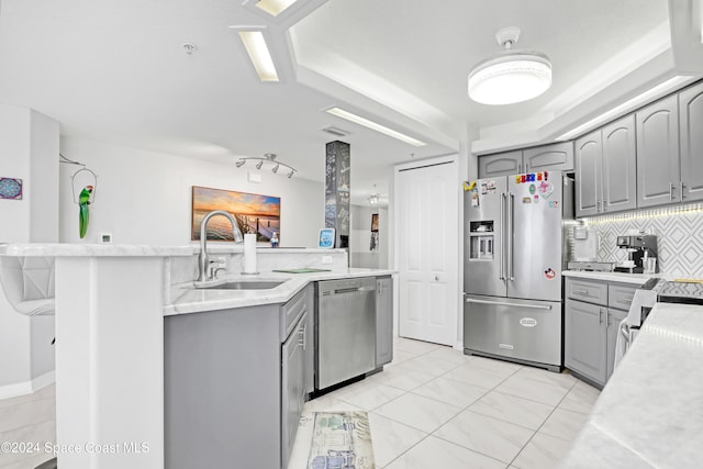 kitchen with backsplash, gray cabinetry, sink, and stainless steel appliances