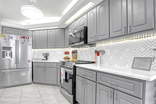 kitchen with gray cabinets, stainless steel appliances, and tasteful backsplash