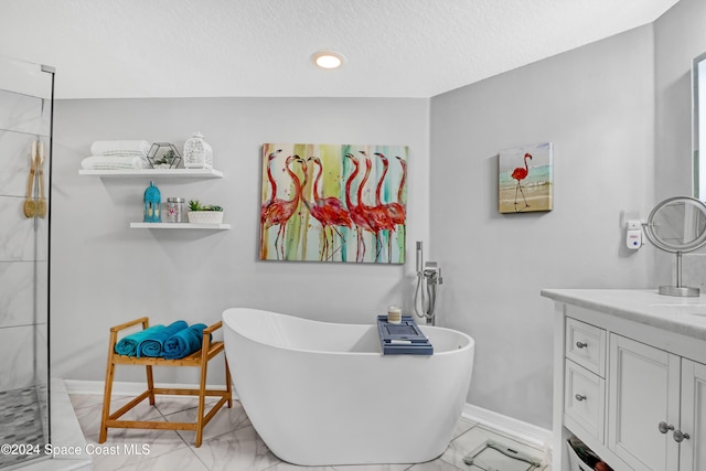 bathroom with a textured ceiling, vanity, and a bath