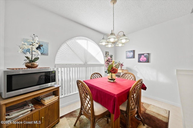 dining area with light tile patterned floors, a textured ceiling, and an inviting chandelier