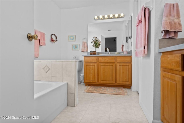 bathroom with tile patterned flooring, vanity, a tub to relax in, and toilet