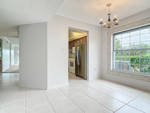 spare room featuring light tile patterned floors, a textured ceiling, and an inviting chandelier