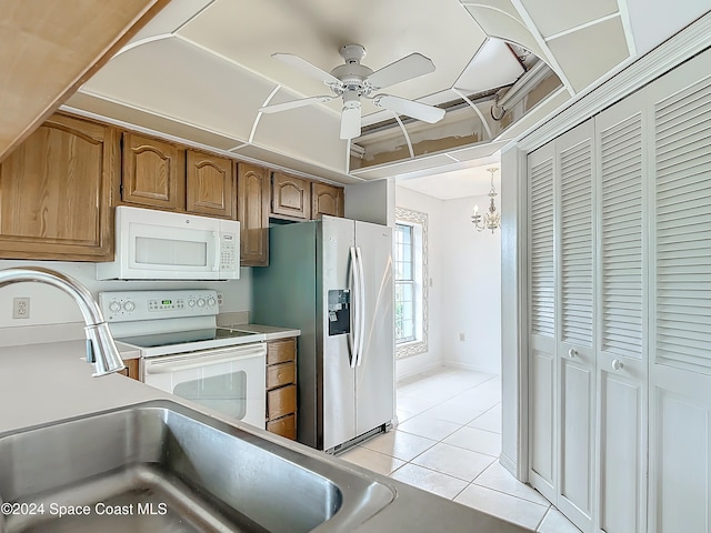 kitchen featuring ceiling fan with notable chandelier, light tile patterned floors, white appliances, and decorative light fixtures