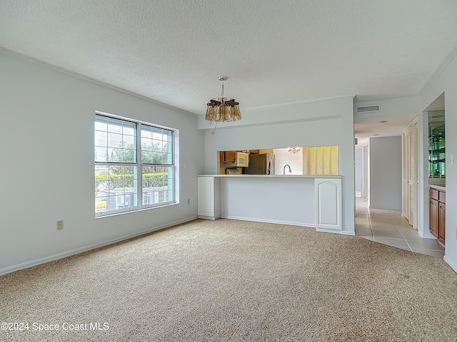 unfurnished living room with light colored carpet, a textured ceiling, and a notable chandelier